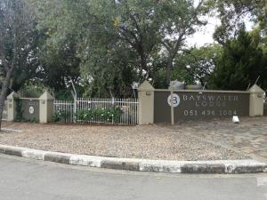 una señal para el lodge de invierno de la bahía frente a una valla en Bayswater Lodge, en Bloemfontein