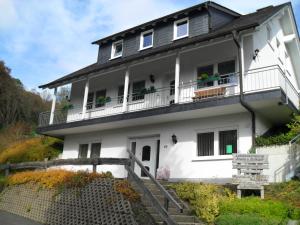 ein weißes Haus mit Balkon auf einem Hügel in der Unterkunft Ferienwohnungen Sonnenpfad in Schmallenberg