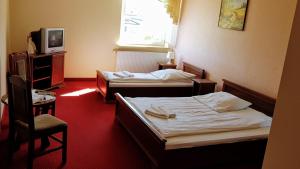 a hotel room with two beds and a tv at Kania Pokoje Gościnne in Przodkowo