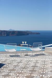 a table and chairs on a balcony with a view of the ocean at Erosantorini Estate in Fira