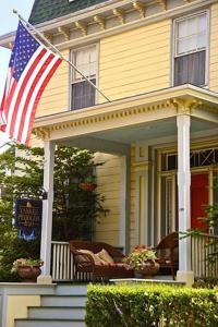 une maison avec drapeau américain sur la terrasse couverte à l'avant dans l'établissement Yankee Peddler Inn, à Newport