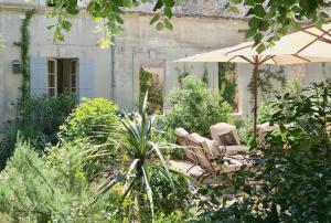 a couple of chairs and an umbrella in a garden at Le Clos Saluces in Avignon