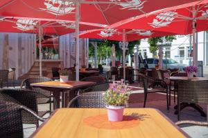 eine Terrasse mit Tischen, Stühlen und roten Sonnenschirmen in der Unterkunft Hotel Deutsche Flagge in Binz