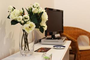 a vase of white flowers sitting on a desk with a computer at Albergue San Lázaro in Sarria