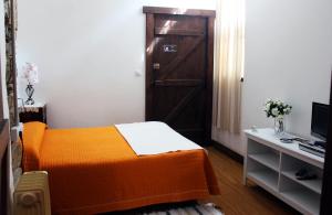 a bedroom with an orange bed and a door at Albergue San Lázaro in Sarria