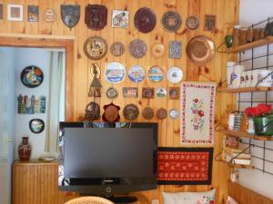 einen TV in einem Zimmer mit Platten an der Wand in der Unterkunft Cozy Family Cottage at the Lake in Siófok