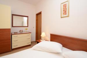 a bedroom with a bed and a dresser and a mirror at Apartments Ranko in Zavalatica