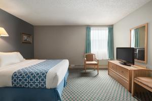 a hotel room with a bed and a flat screen tv at Travelodge by Wyndham Edmonton Airport in Leduc