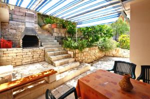 a patio with a stone fireplace and a table with chairs at Apartments Ranko in Zavalatica