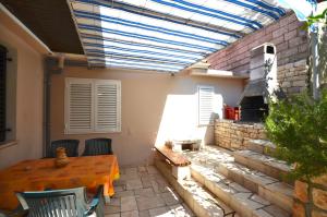 a patio with a wooden table and a stove at Apartments Ranko in Zavalatica