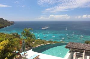 a swimming pool with a view of the ocean and boats at Tropical Hideaway in Port Elizabeth