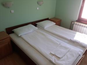 a bedroom with two beds with white sheets and towels at Apartments Markoni in Zlatibor