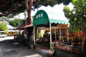 a bar with a green awning on a street at Camping Roma in Ventimiglia