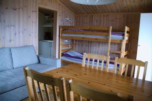 Cette chambre comprend une table, un canapé et des lits superposés. dans l'établissement Frykenbadens Camping, à Kil