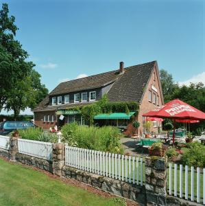 a white fence in front of a house with a building at Zum Eichenfrieden in Rade