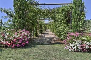 a garden with flowers and an arch with a pathway at Taverna di Bibbiano in Colle di Val d'Elsa