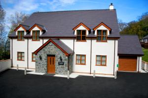 uma grande casa branca com garagem em Sycamore Cottage em Penmaen-mawr