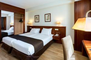 a hotel room with a bed, chair, and nightstand at Rafaelhoteles Ventas in Madrid