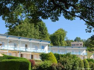 a large white building with bushes and trees at Les Fées du lac *** in Nages