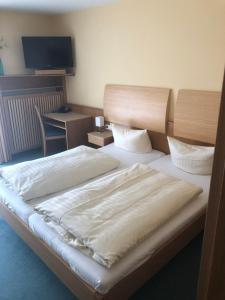 a bedroom with a bed and a desk with a television at hotel zentlinde in Mossautal