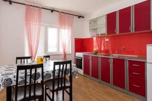 a kitchen with red cabinets and a table with chairs at Apartments G&M in Vodice