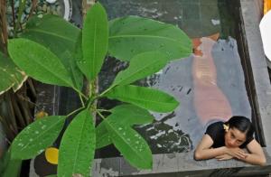 a woman laying on a ledge next to a plant at The Patio Yogya in Yogyakarta