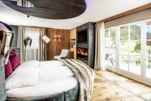 a bedroom with a white bed and a fireplace at Alpine Luxury SPA Resort Schwarzenstein in Lutago