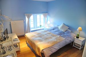 een blauwe slaapkamer met een bed en een raam bij La Borlonette in Durbuy