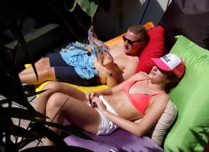 two men and a woman in swimsuits laying on beds at The Patio Yogya in Yogyakarta