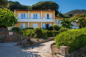 uma grande casa amarela com arbustos à frente em Hôtel-Club du Domaine d'Aiguebelle, USSIM Vacances em Le Lavandou