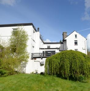 une maison blanche avec une haie devant elle dans l'établissement Gallt y Glyn Hostel, à Llanberis