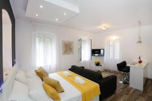 a white bedroom with a bed and a living room at Studio Apartman Fictilis in Split