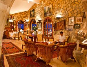 a man sitting in a room with a stone wall at Bellapais Gardens in Kérynia