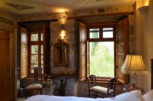 1 dormitorio con cama, ventana y espejo en Archontiko Chioti, en Leonidio