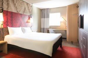 a hotel room with a large bed and a large window at ibis Paris Gare du Nord Château Landon 10ème in Paris