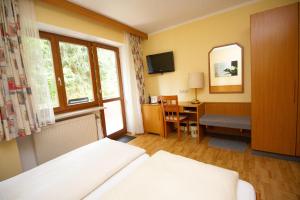 a hotel room with a bed and a desk and a window at Hotel am Wald in Ottobrunn