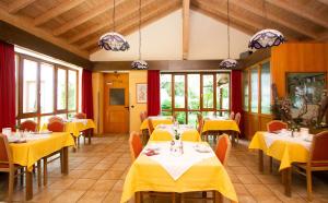 a restaurant with yellow tables and chairs and windows at Hotel am Wald in Ottobrunn