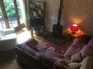 a living room with a couch and a wood stove at Yr Hen Feudy in Barmouth