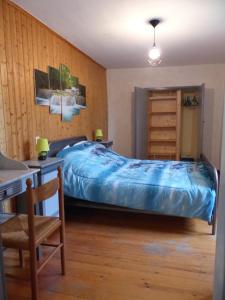 1 dormitorio con cama, escritorio y silla en Appartement La Tour, en Embrun