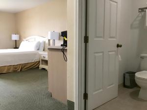 1 dormitorio con 1 cama, aseo y puerta en Rogue Regency Inn & Suites, en Medford