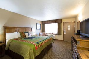 a hotel room with a bed and a flat screen tv at Crosswinds Inn in West Yellowstone