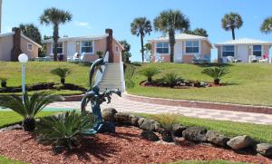 a statue in front of a house with palm trees at Shoreline Suites & Cabana Cottages – Beachfront in Daytona Beach