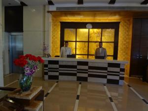 ムンバイにあるGrand Residency Hotel & Serviced Apartmentsのロビーのフロントデスクに立つ二人