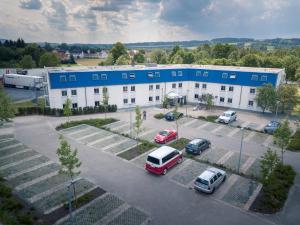 un grand bâtiment avec des voitures garées dans un parking dans l'établissement Auszeit Das Hotel Himmelkron, à Himmelkron
