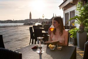 uma mulher sentada à mesa a beber um copo de vinho em Hotel Bucintoro em Veneza