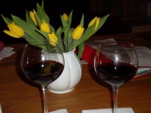 two glasses of wine and a vase of yellow flowers at Ferienwohnung Friesenstall in Heede