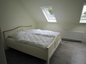 a white bed in a room with two windows at Ferienwohnung Friesenstall in Heede