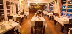 un ristorante con tavoli e sedie bianchi in una stanza di Hotel l'Impératrice a Fort-de-France