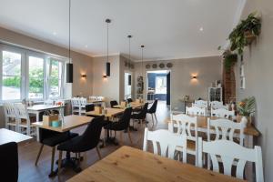 un restaurante con mesas de madera y sillas blancas en Hotel Barbarossa Classic, en Ratingen