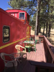 a deck with chairs and tables and a red train at The Canyon Motel & RV Park in Williams